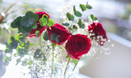 Red Roses bouquet, blooming roses in a crystal vase on a table. Rose flowers bunch in sun light, nature. Holiday gift, Bunch of roses flower. Holiday backdrop, birthday, wedding boの写真素材