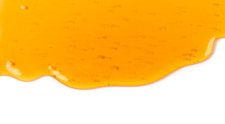 Honey dripping, pouring, flowing over white background. Close-up. Healthy organic liquid sweet sticky honey dipping, isolated on white, closeup. Border art design.の写真素材