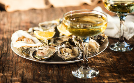 Fresh Oysters with champagne close up, over wood background, open french Fine de Claire oysters. Dinner in a restaurant, sea food. Served table with Oyster. Gourmet food, delicatesの写真素材