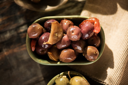 Olives, homemade marinated colorful olives with herbs and spices on rustic table, close up. Healthy Mediterranean vegan food. Top view, flat layの写真素材