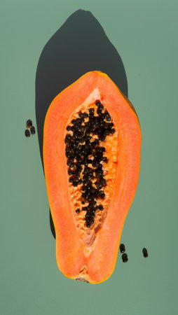 Papaya fruit over green background, fresh exotic fruits with seeds. Halved fresh organic Papaya exotic fruit art design, close up. Top view, vertical image.の写真素材
