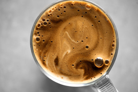 Coffee cup from above, Espresso foam texture, creamy coffee, rich, freshly brewed cup of hot latte. Top view of cappuccino milk foam closeup. Creamy coffee macro shot, on a grey taの写真素材