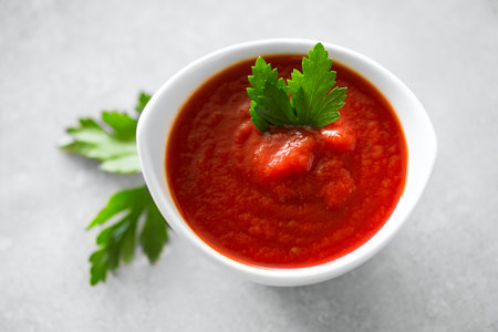 Tomato sauce, Homemade tomato paste in a white bowl and fresh ingredients on a grey table. Ketchup, Red sauce for pizza or pasta made from fresh bio tomatoes. Top viewの写真素材