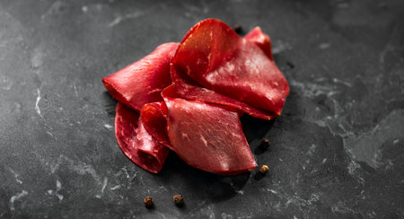 Black angus dried beef, slices of aged, delicatessen, snack on black marble background, top view. Close upの写真素材