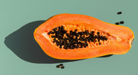 Papaya fruit over green background, fresh exotic fruits with seeds. Halved fresh organic Papaya exotic fruit art design, close up. Top viewの写真素材