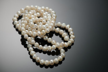 Pearl necklace over black background, close up. Beautiful Natural pearls beads, elegant accessories macro shot. Pearl gemstones, glamour. Top viewの写真素材