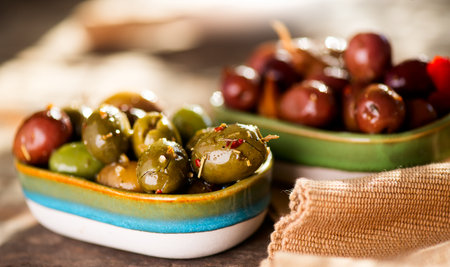 Olives, homemade marinated colorful olives with herbs and spices on rustic table, close up. Healthy Mediterranean vegan food, appetizer, macro shotの写真素材