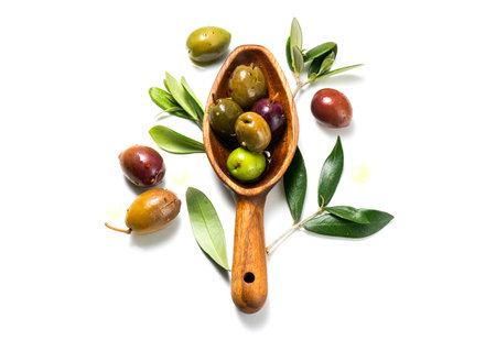 Olives, homemade marinated colorful olives with herbs and spices isolated on white background, in a rustic wooden spoon, close up. Healthy Mediterranean vegan food. Top view, flatの写真素材