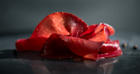 Black angus dried beef, slices of aged wagyu, delicatessen, snack on black marble background. Close up, macro shotの写真素材