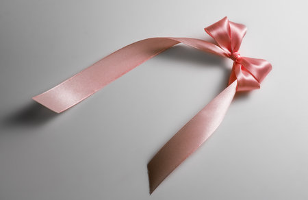 Pink satin gift bow on grey background. Holiday decoration silk ribbon, top view. Pastel color gift designの写真素材