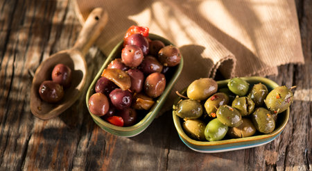 Olives, homemade marinated colorful olives with herbs and spices on rustic table, close up. Healthy Mediterranean vegan food, top view, flat layの写真素材