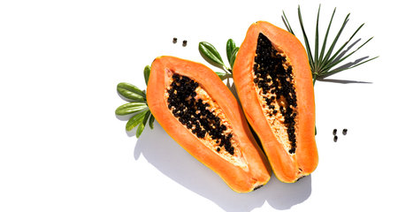 Papaya fruit isolated on white background, fresh exotic fruits with leaves and seeds. Halved fresh organic Papaya exotic fruit art, close up. Top view, border design, flat layの写真素材