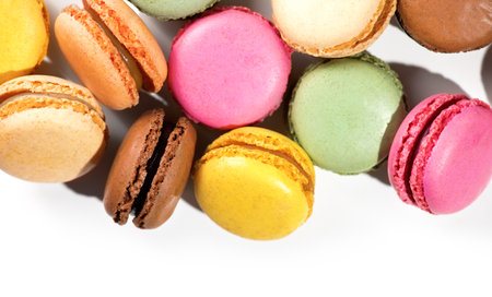 Colorful macarons assortment featuring vibrant pink, yellow, green, and brown French pastries creamy fillings, macaroon isolated on white background, flat lay, top view, border desの写真素材