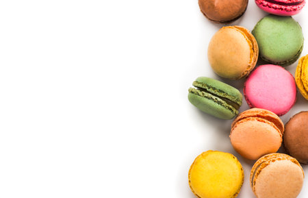 Macarons, macaroons, colorful assortment border design, vibrant pink, yellow, green, brown French pastries creamy fillings, macaroon isolated on white background, flat lay, top vieの写真素材