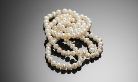Pearl necklace over black background, close up. Beautiful Natural pearls beads, elegant accessories macro shot. Pearl gemstones, glamour. Top view.の写真素材