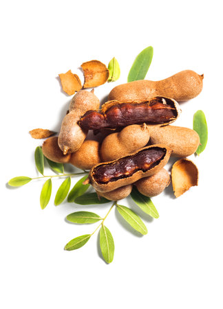 Tamarind tropical fruits isolated on white background. Fresh Tamarind pods with leaves (Tamarindus indica, Indian date), healthy vegan food close up, top view, flat lay , verticalの写真素材