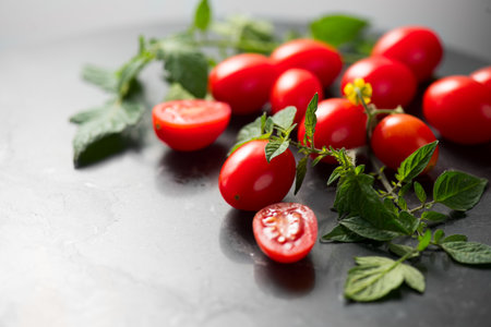 Cherry tomatoes, tomato Fresh Ripe little tomatoes close-up. Vegetables, Organic tomato with leaves over black marble table background. Cooking concept.の写真素材