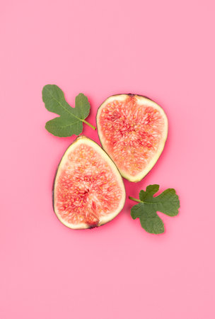 Fig fruits. Ripe sweet fresh figs fruit with leaves close up, on pink background, flat lay, top viewの写真素材