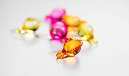 Cosmetic capsules hair oil care, vitamins, colorful liquid-filled capsules, oil, serum, pink and...