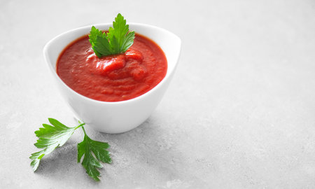 Tomato paste, sauce, Homemade tomato paste in a white bowl and fresh ingredients on a grey table. Ketchup, Red sauce for pizza or pasta made from fresh tomatoes. Border designの写真素材