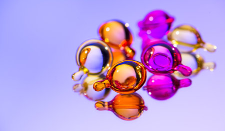 Cosmetic capsules, hair care oils, colorful liquid-filled capsules, oil, serum, pink and yellow varieties, glossy, reflective violet surface. Capsules background, vibrant, modern aの写真素材