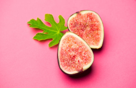 Fig fruits. Ripe sweet fresh figs fruit with leaf close-up, on pink background, flat lay, top viewの写真素材