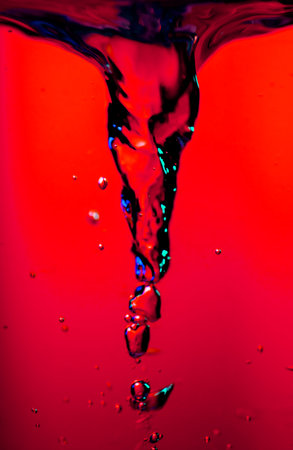 Water swirl storm twister, underwater vortex on vivid red background, whirlpool, storm tornado twister typhoon vortex in a fresh water, spin, splash with bubbles, vertical shot.の写真素材