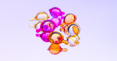 Cosmetic capsules for face or hair care, colorful liquid-filled capsules, oil, serum, pink and yellow varieties, glossy, reflective surface. Capsules background, vibrant, modern aeの写真素材