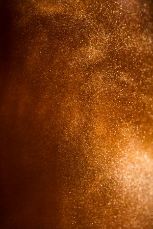 The photo of Gold particles floating background, golden abstract backdrop. Beautiful metallic yellow dust texture, Metallic paint close-up. Art Wallpaper waves suの写真素材