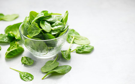 Spinach leaves in a transparent glass bowl isolated on white background. Heap of Baby spinach fresh...