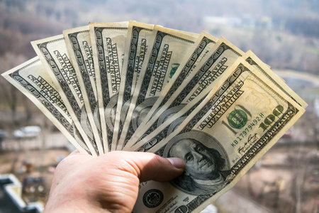 One hundred dollar banknotes in man hand with cityscape in the background. Business success concept....