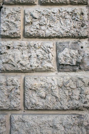 Rough textured plaster wall coating, imitation of stone masonry. Abstract grey patchy background.