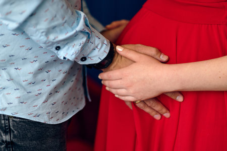 Guy and pregnant girl hold hands on their bellyの写真素材