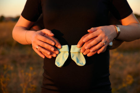 Guy and pregnant girl hold hands on their belly