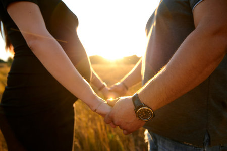 Guy and pregnant girl hold hands on their bellyの写真素材