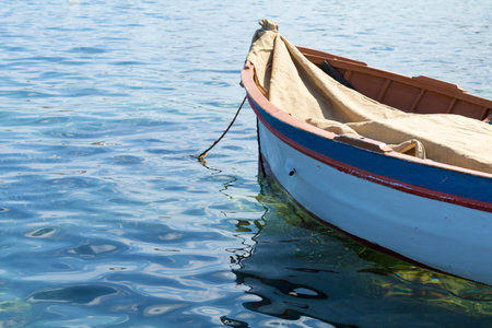 Colorful traditional Maltese fishing boat (Luzzu) moored in harbor, beautiful blue mediterranean...