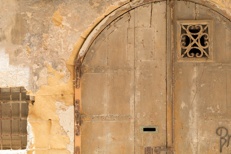 Old distressed yellow wooden double-door, in Maltese Limestone wall, shot straight-on in Valletta, Malta, Europe. Used in the 2015 filming of the Assassin's Creed movie.の写真素材