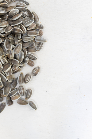 raw organic white and black freshly harvested sunflower seeds on white painted wooden rustic table with copy spaceの写真素材
