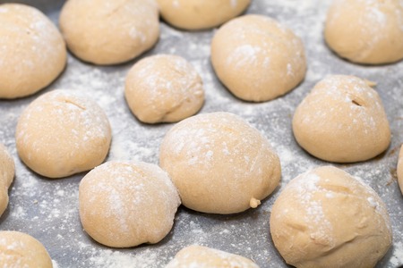 Authentic home kitchen, freshly made white bread rolls proving sprinkled with with flour ready for baking on trayの写真素材