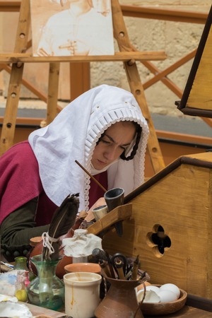 Medieval reenactor in scribe costume practicing traditional illumination writing calligraphy with feather quill and ink, Mdina, Malta, April 2017のeditorial素材