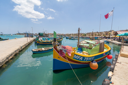 Traditional colourful Maltese Luzzu fishing boats in the turquoise blue water of Marsaxlokk harbour, Marsaxlokk, Malta, June 2017のeditorial素材