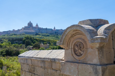 Old burial crypt cemetery below the Ancient hilltop fortified capital city of Malta, The Silent City, Mdina or L-Imdina, it's skyline against blue skies with huge walls, domes and towers, March 2017の写真素材