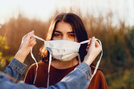 Beautiful Women In A Medical Mask. Close-up of a young woman with a surgical mask on her face against SARS-cov-2.の写真素材
