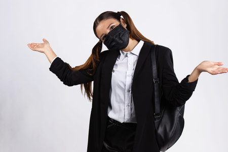 Optimistic european brunette girl in face mask showing empty open hands