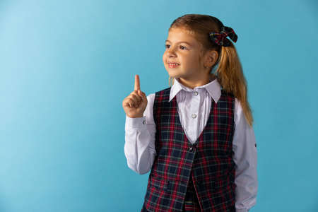 Little girl has an idea on blue background .School uniform .の写真素材