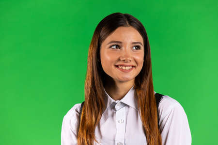 Portrait of brunette woman in white shirt looking far away distance isolated on green background, studio shootingの写真素材