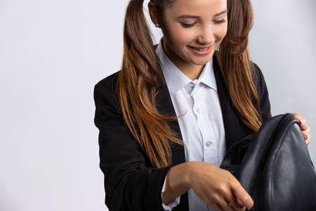 Smiling caucasian girl with long hair, looking for something interesting. Stylish young 20s girl checking her black bagの写真素材
