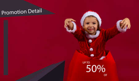 Holidays, sale, christmas and shopping concept - pretty little girl sitting in christmas sale bag with percent signの写真素材