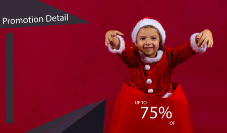 Handsome little girl sitting in christmas sale shopping bag with 75 percent sign. Holidays, sale, christmas and shopping concept with empty space. High quality photoの写真素材