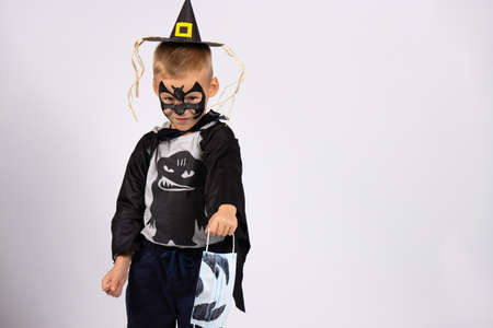 Happy but unusual halloween. The pandemic and prohibitions are taking away childhood from children. Halloween bat gives away mask, tired of quarantine.の写真素材